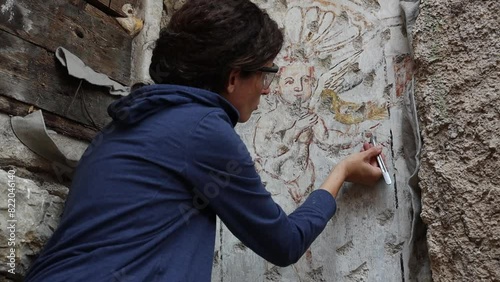 Expert female Restorer Working on a Gothic Fresco on an External Wall of Ajdovscina Town in Vipava valley Slovenia photo