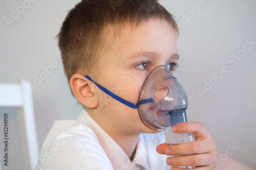 Children's lung health. Boy breathes into an inhalation mask. Childhood diseases. Self-medication of respiratory tract with an inhalation nebulizer at home.