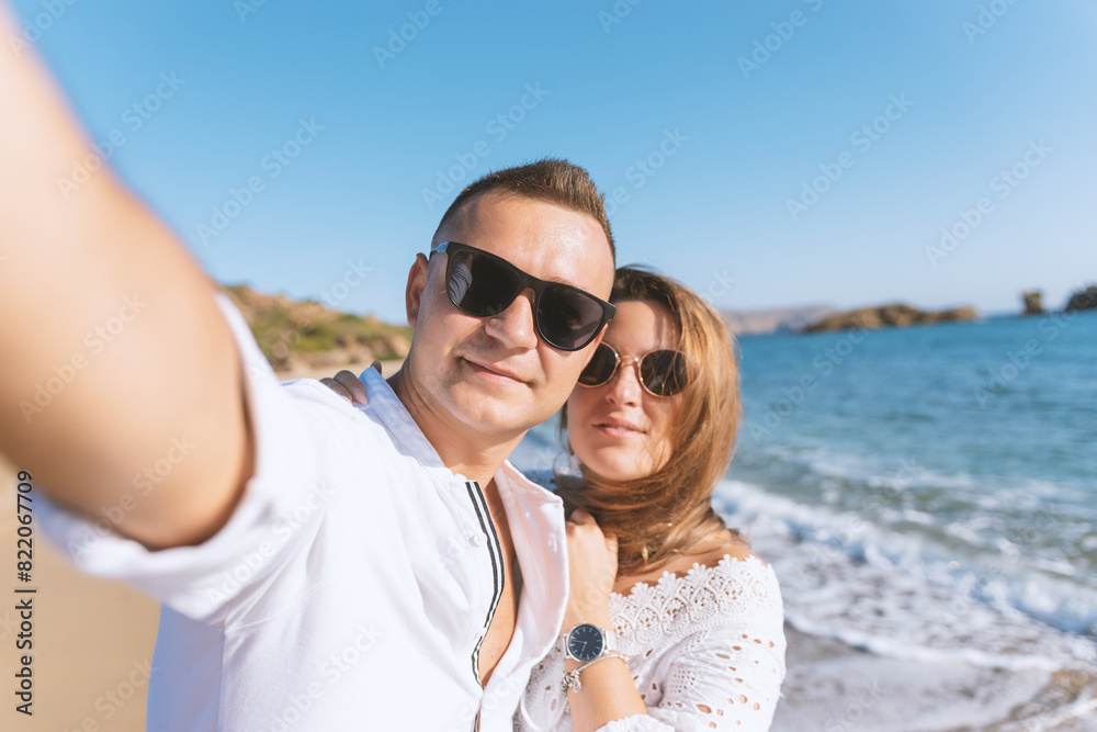 Young happy couple taking selfie on the beach. Summer vacations concept. Young happy couple taking selfie on the beach. Summer vacations concept.