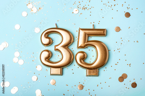35 years celebration. Greeting banner. Gold candles in the form of number thirty five on blue background with confetti.