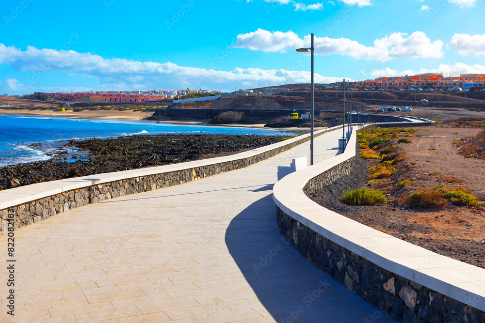 A paved walkway in Fuerteventura, Canary Islands, overlooking the Atlantic Ocean. Paved walkway winding along coastline