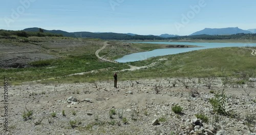 Aerial view of dry reservoir with woman hiking in remote mountains, hills, and rocky path, Andalusia, Spain. photo