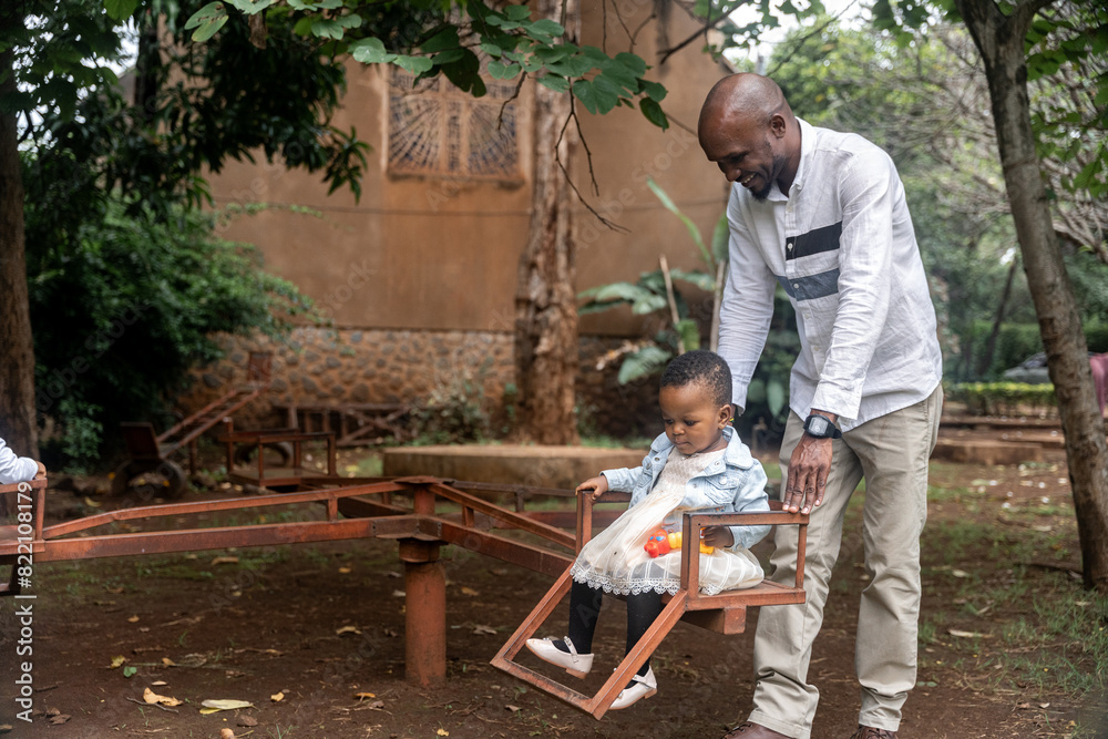 African father and baby girl playing in an old playground African father and baby girl playing in an old playground
