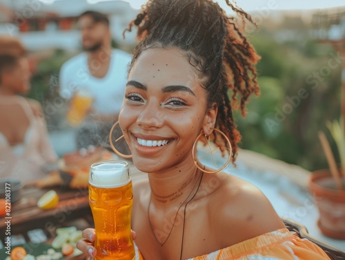 A smiling person enjoys a drink outdoors with friends, evoking a carefree and joyous atmosphere