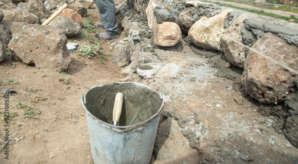 Unfinished rough stone wall in outdoor. Construction Unfinished rough stone wall in outdoor. Construction