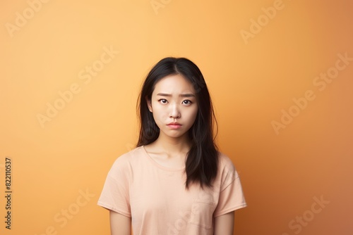 Peach background sad Asian Woman Portrait of young beautiful bad mood expression Woman Isolated on Background depression anxiety fear burn out  © Zickert