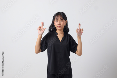 Portrait of attractive Asian woman in casual shirt sweating with her hand on her chest and fingers up, making an oath of loyalty. Isolated image on white background photo