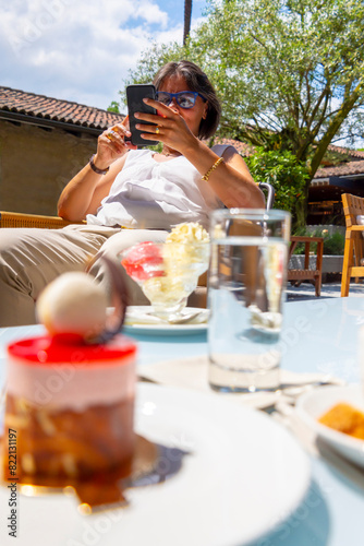 Dessert and Woman Using Phone in a Sunny Day in an Outdoor Restaurant in Switzerland.