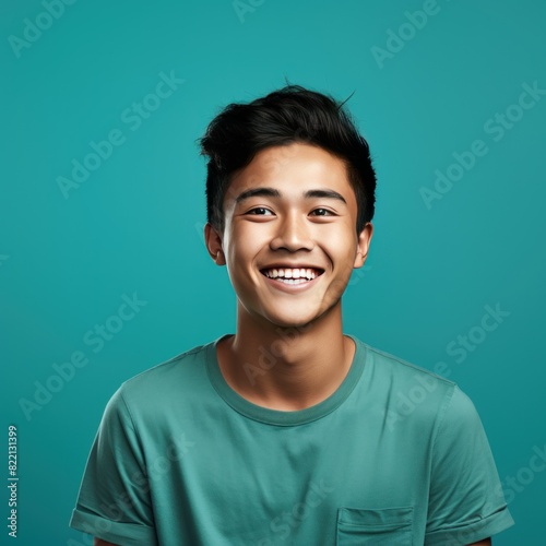 Teal Background Happy asian man realistic person portrait of young teenage beautiful Smiling boy good mood Isolated on Background ethnic diversity equality acceptance concept with copyspace