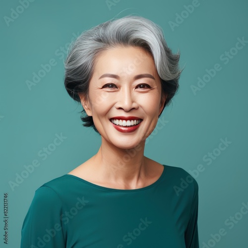 Teal Background Happy Asian Woman Portrait of Beautiful Older Mid Aged Mature Smiling Woman good mood Isolated Anti-aging Skin Care Face Beauty Product Banner with copyspace  © Zickert