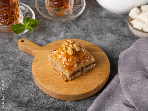 Walnut baklava. Traditional Middle Eastern Flavors. Traditional Turkish baklava. fistikli baklava with Turkish tea on dark background photo