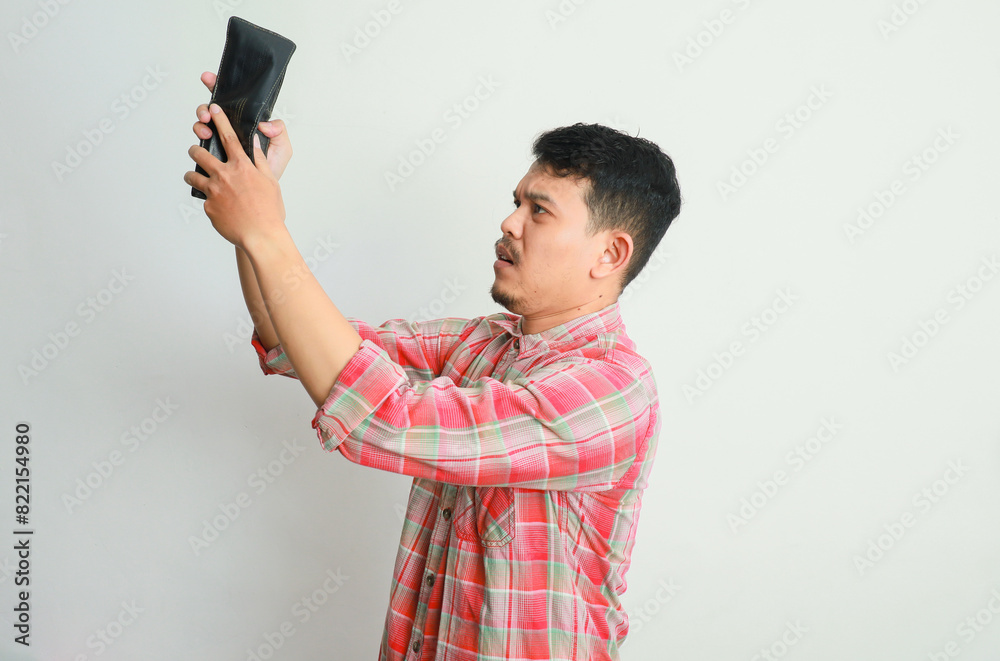 Young asian man looking in his wallet but no money feels shocked Young asian man looking in his wallet but no money feels shocked
