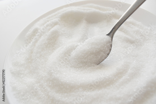 Foto White refined granulated sugar on spoon.