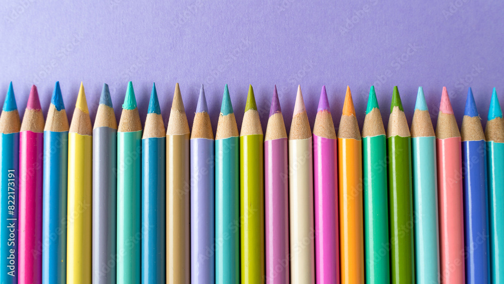 Colorful wooden crayons on a purple paper background Colorful wooden crayons on a purple paper background