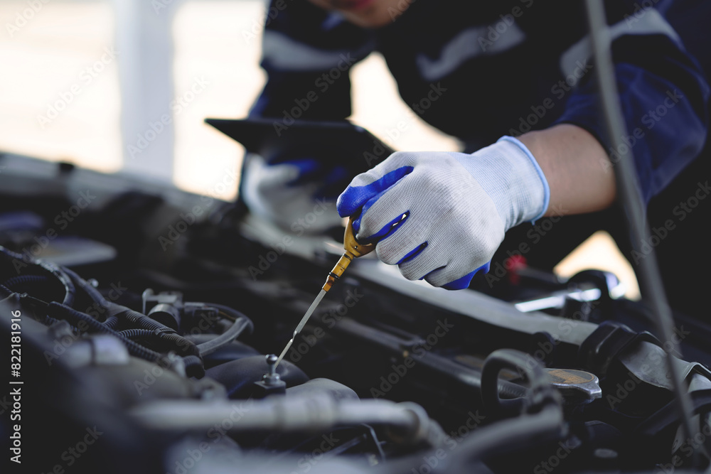 Auto mechanic checking oil in car engine Technician inspects and maintains car engines. Auto mechanic checking oil in car engine Technician inspects and maintains car engines.