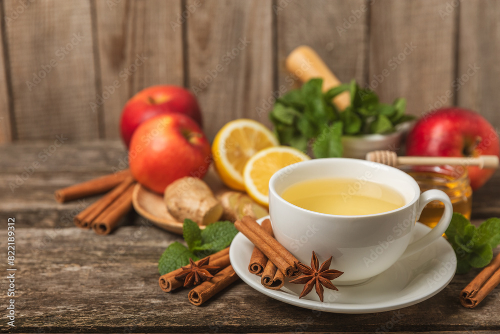 Fragrant hot tea with cinnamon stick and anise on a textured wooden background. A cup of hot tea with honey, lemon, mint and apples. Spicy tea with spices. Immunity tea. Health concept.Copy space. Fragrant hot tea with cinnamon stick and anise on a textured wooden background. A cup of hot tea with honey, lemon, mint and apples. Spicy tea with spices. Immunity tea. Health concept.Copy space.