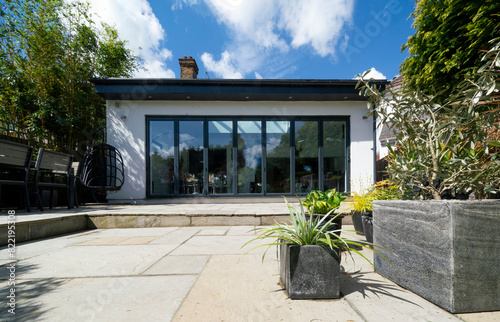 Stylish, closed, bifold doors with plants in summer, spring, with Indian Sandstone patio. photo