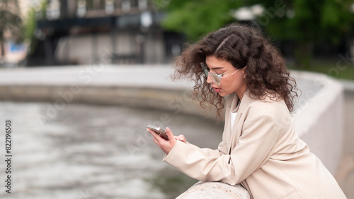 Beautiful business woman portrait in summer in the city with a phone in her hands