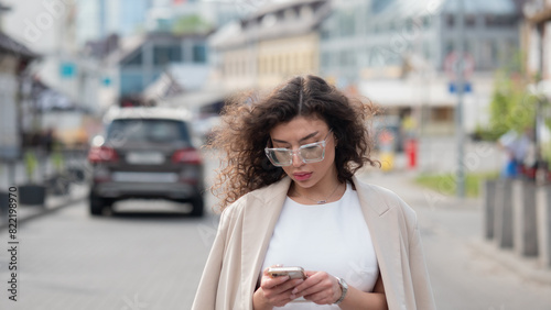 Beautiful business woman portrait in summer in the city with a phone in her hands