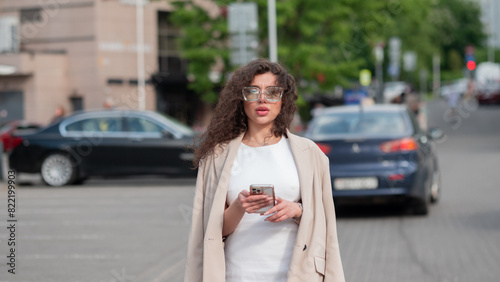 Beautiful business woman portrait in summer in the city with a phone in her hands