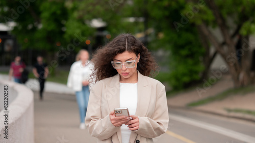 Beautiful business woman portrait in summer in the city with a phone in her hands