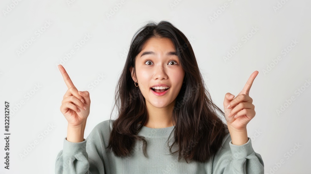 Asian woman pointing her hand up and looking above her head Asian woman pointing her hand up and looking above her head