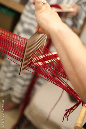 Artisan Weaving Red Thread on Wooden Loom Indoors in Daylight. Ukrainian Cultural authenticity