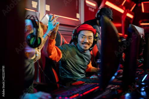 Happy Asian gamer celebrating with teammates at a competitive gaming event photo