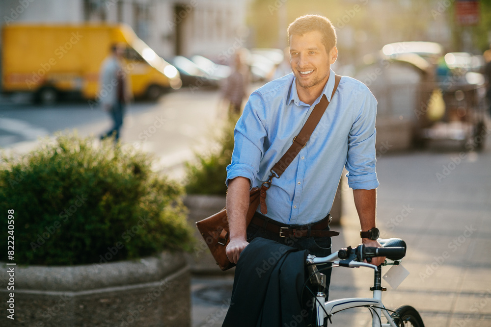 Smiling young businessman riding a bicycle in city Smiling young businessman riding a bicycle in city