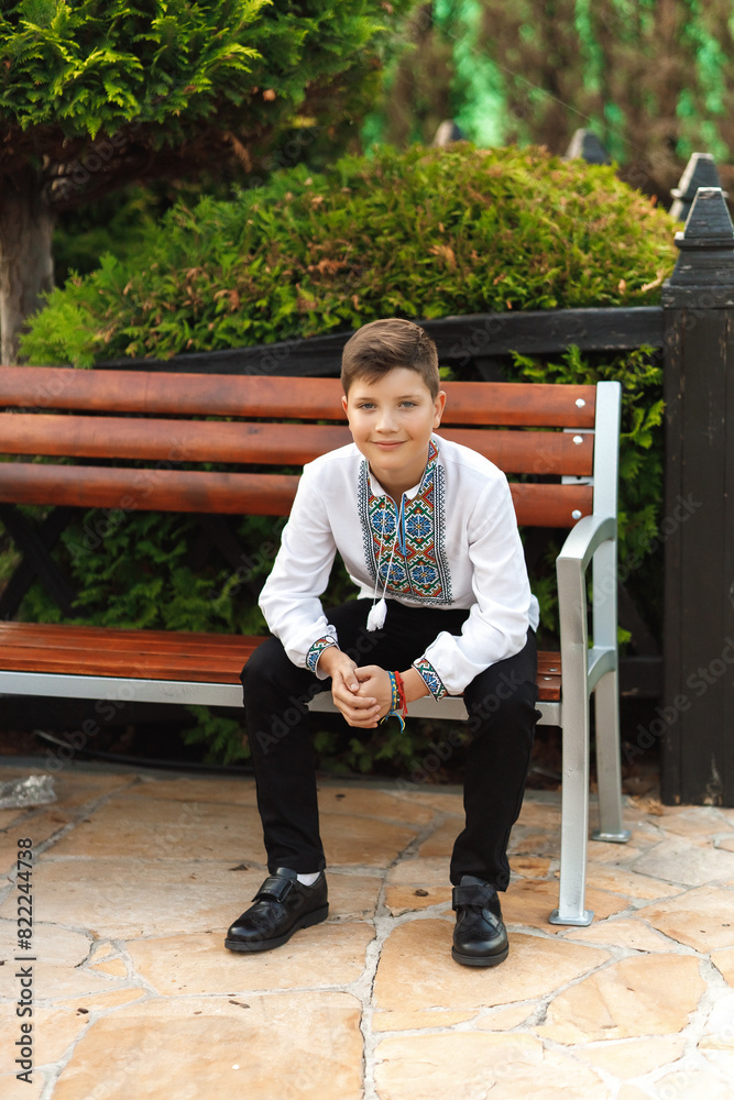 young teenager in an embroidered shirt sitting in the park