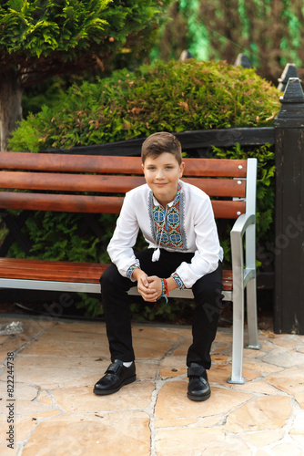 Obraz na płótnie young teenager in an embroidered shirt sitting in the park w salonie