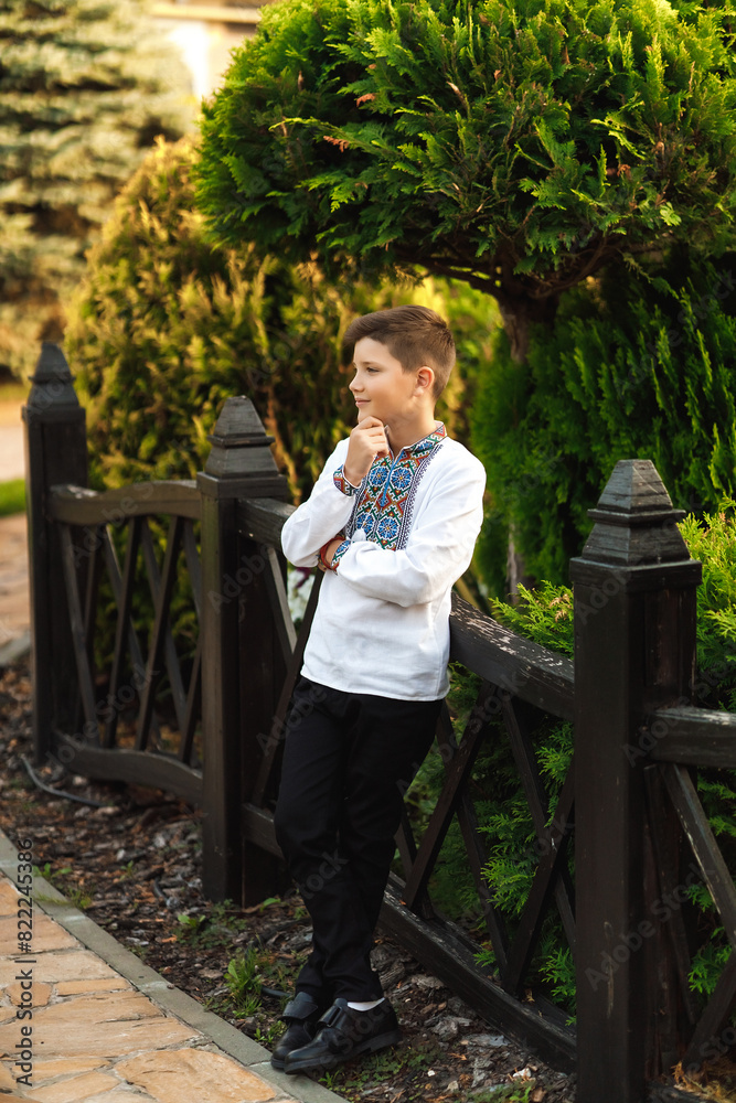Young teenager in an embroidered shirt posing in a summer park
