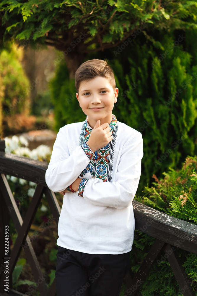 Young teenager in an embroidered shirt posing in a summer park
