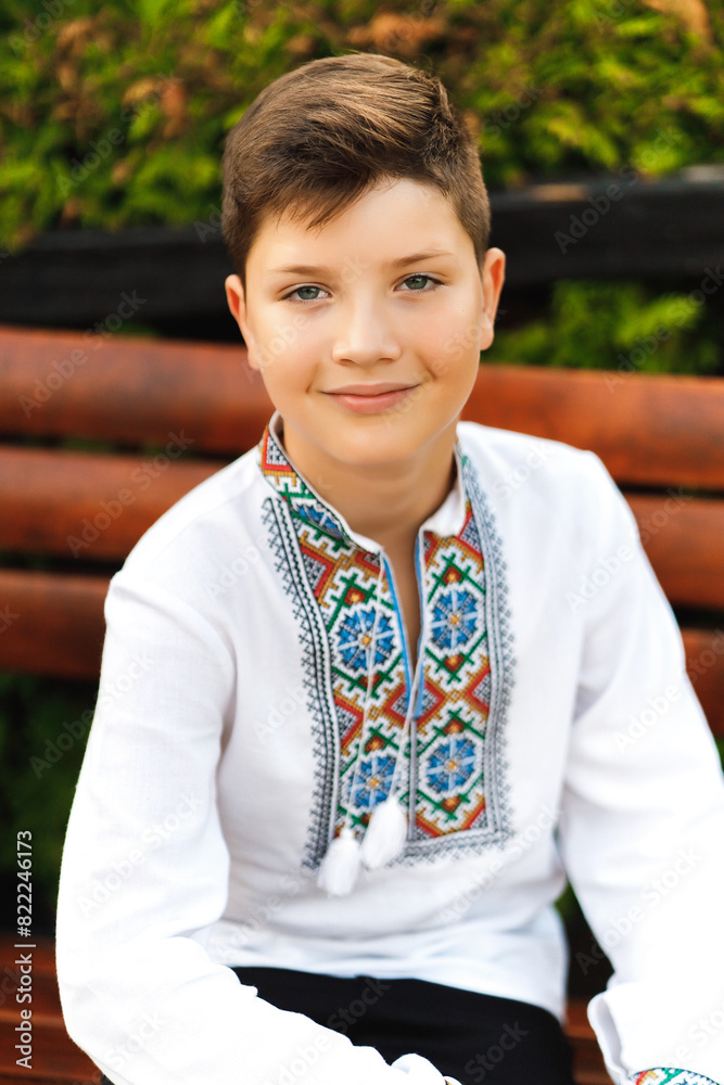 young teenager in an embroidered shirt sitting in the park