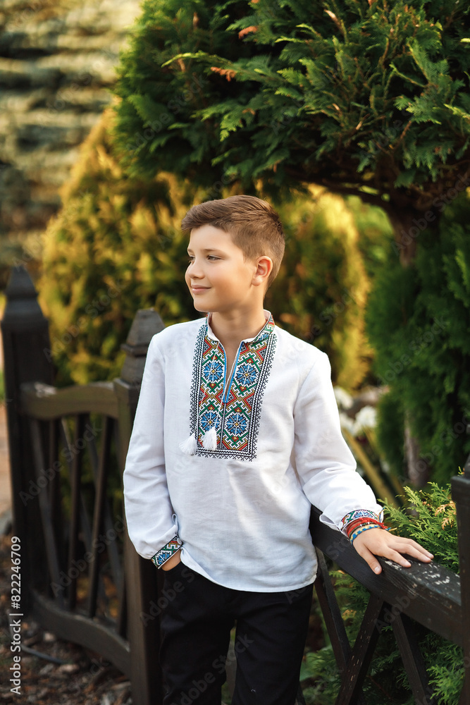 Young teenager in an embroidered shirt posing in a summer park