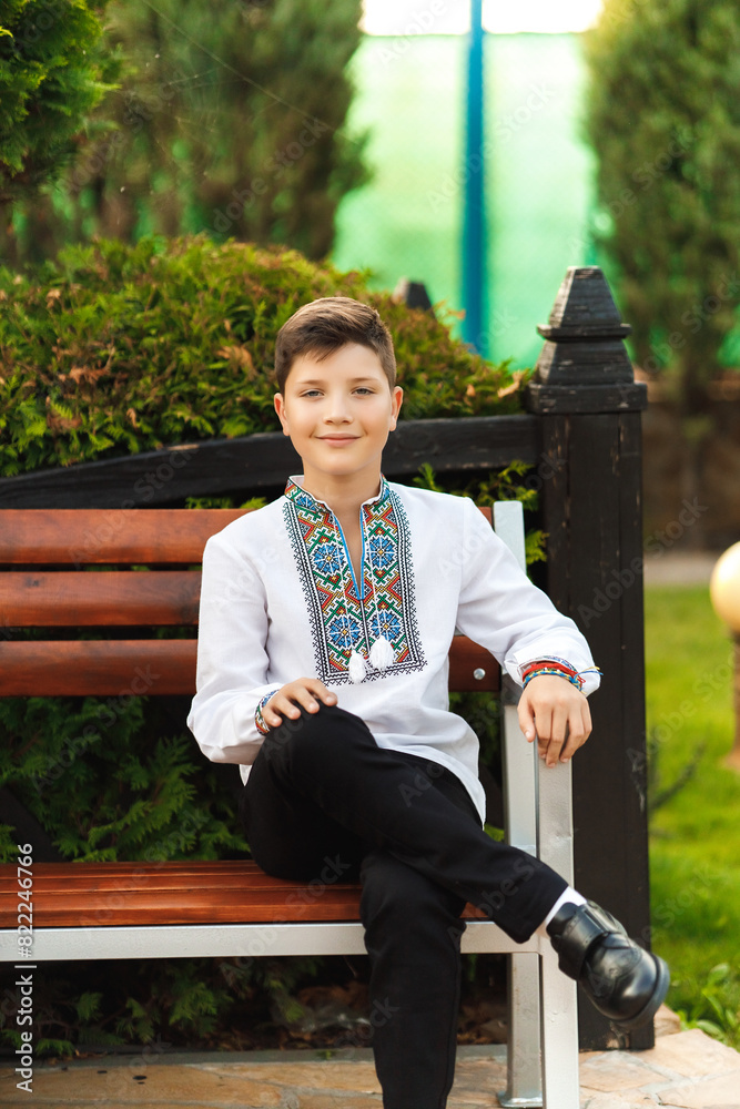 young teenager in an embroidered shirt sitting in the park