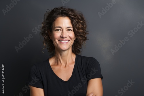 Portrait of a grinning woman in her 40s smiling at the camera over blank studio backdrop © Markus Schröder