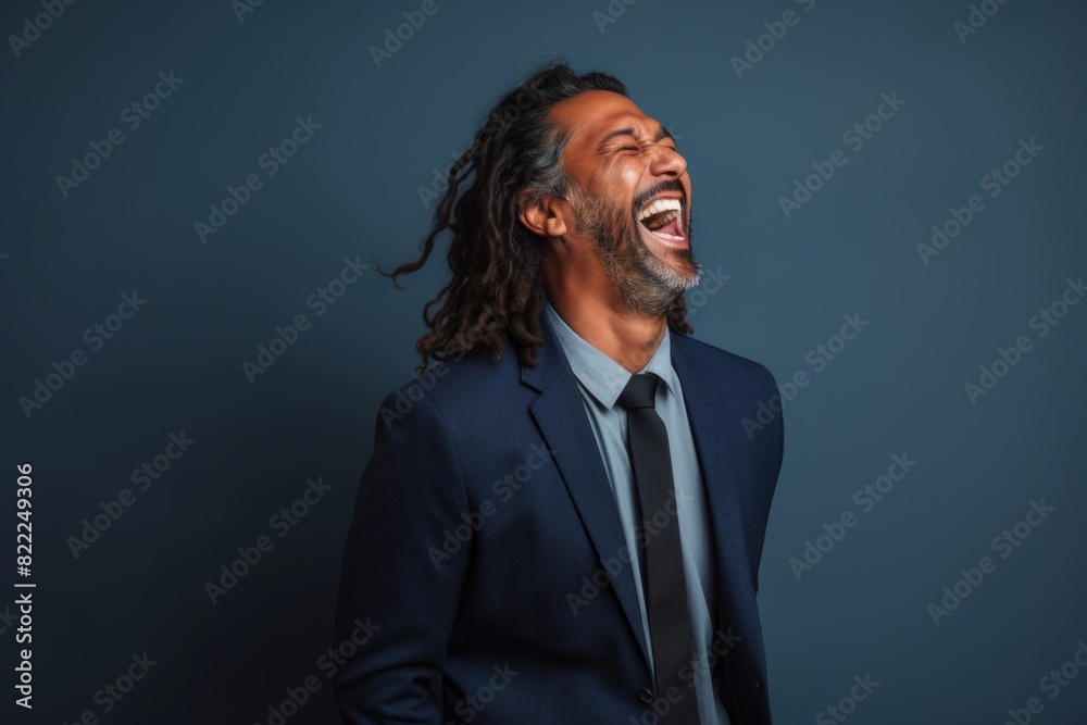 Fototapeta premium Portrait of a tender indian man in his 40s laughing while standing against blank studio backdrop