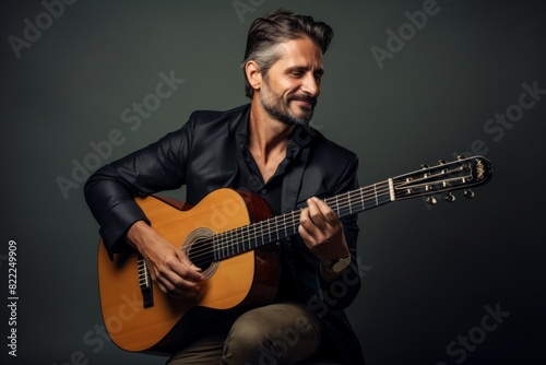 Portrait of a satisfied man in his 40s playing the guitar in blank studio backdrop