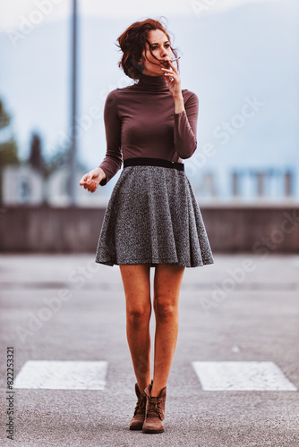 Brown top, grey skirt, thoughtful expression, blurred background