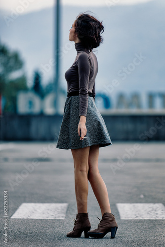 Woman in skirt and top, standing pensively