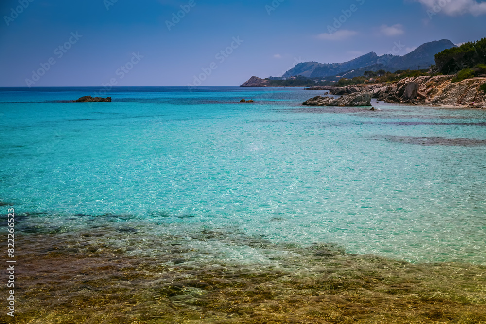 A clear turquoise sea with visible rocks beneath the shallow water - a serene coastal scene from Mallorca