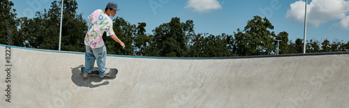 A young skater boy rides a skateboard up the ramp in an outdoor skate park on a sunny summer day.