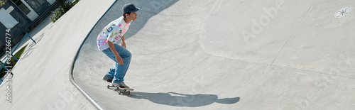 A young skater boy fearlessly accelerates down the ramp at a skate park on a sunny summer day.