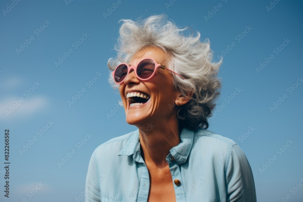 Portrait of a content afro-american woman in her 70s laughing isolated in blank studio backdrop Portrait of a content afro-american woman in her 70s laughing isolated in blank studio backdrop