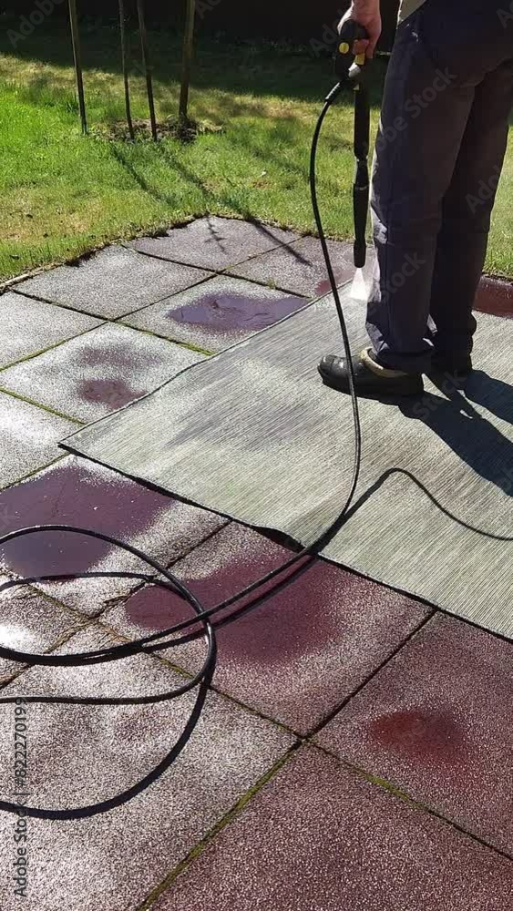 Washing carpet on rubber flooring in backyard. Man cleaning stone garden paths with high pressure power washer. Vertical video. Taken from hand. High quality 4k footage Washing carpet on rubber flooring in backyard. Man cleaning stone garden paths with high pressure power washer. Vertical video. Taken from hand. High quality 4k footage