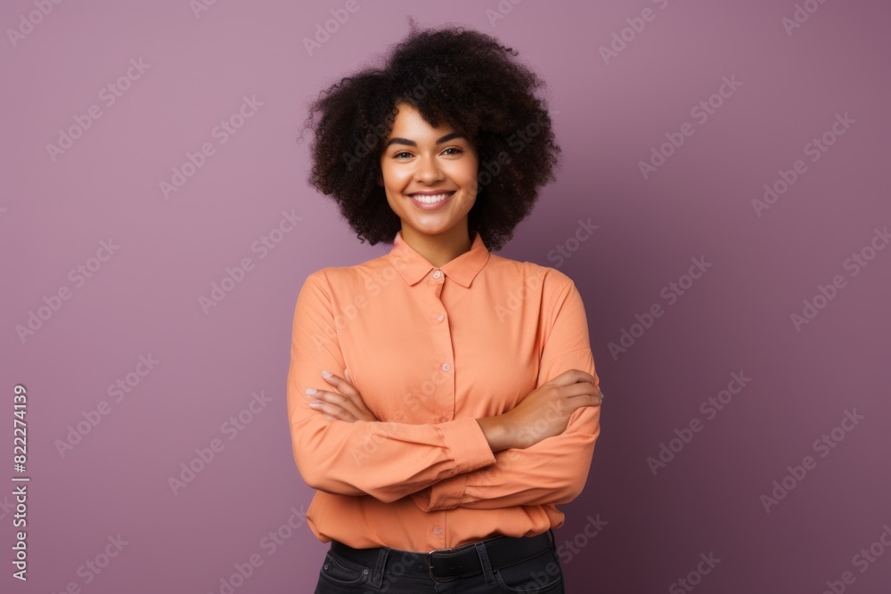 Portrait of a joyful afro-american woman in her 20s with arms crossed over blank studio backdrop