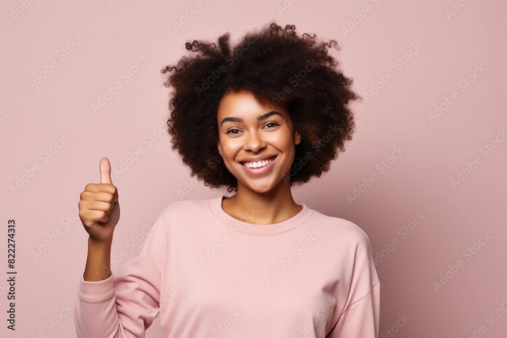Portrait of a glad afro-american woman in her 20s showing a thumb up in blank studio backdrop Portrait of a glad afro-american woman in her 20s showing a thumb up in blank studio backdrop