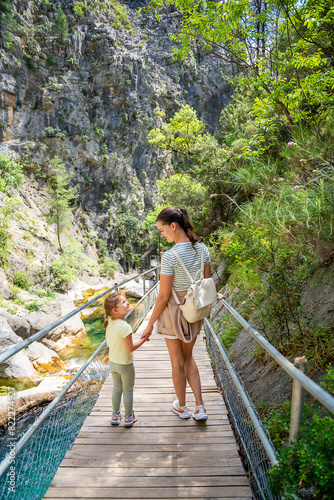 Mother with little girl hiking in Sapadere canyon with wooden paths and cascades of waterfalls in the Taurus mountains, Turkey. Eco tourism concept