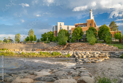 Poudre River at a whitewater park in downtown of Fort Collins Colorado with Powerhouse Energy Campus of Colorado State University in background, spring scenery photo